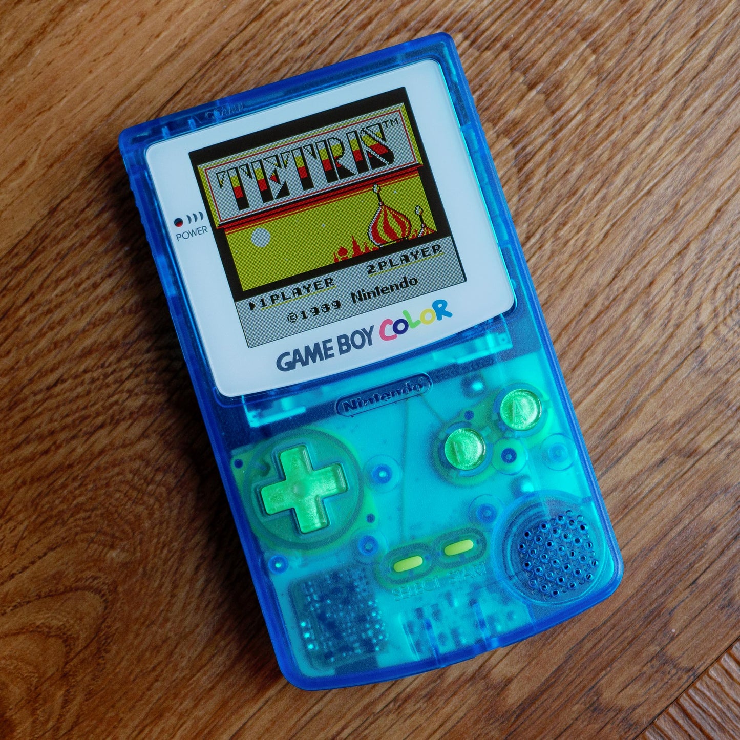 Game Boy Color with a transparent blue casing displaying the Tetris game on its screen robot retro