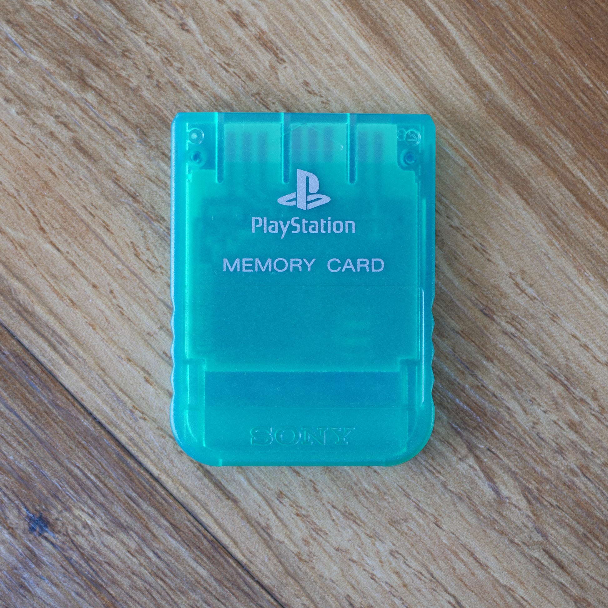 Clear Green PlayStation memory card on a wooden surface