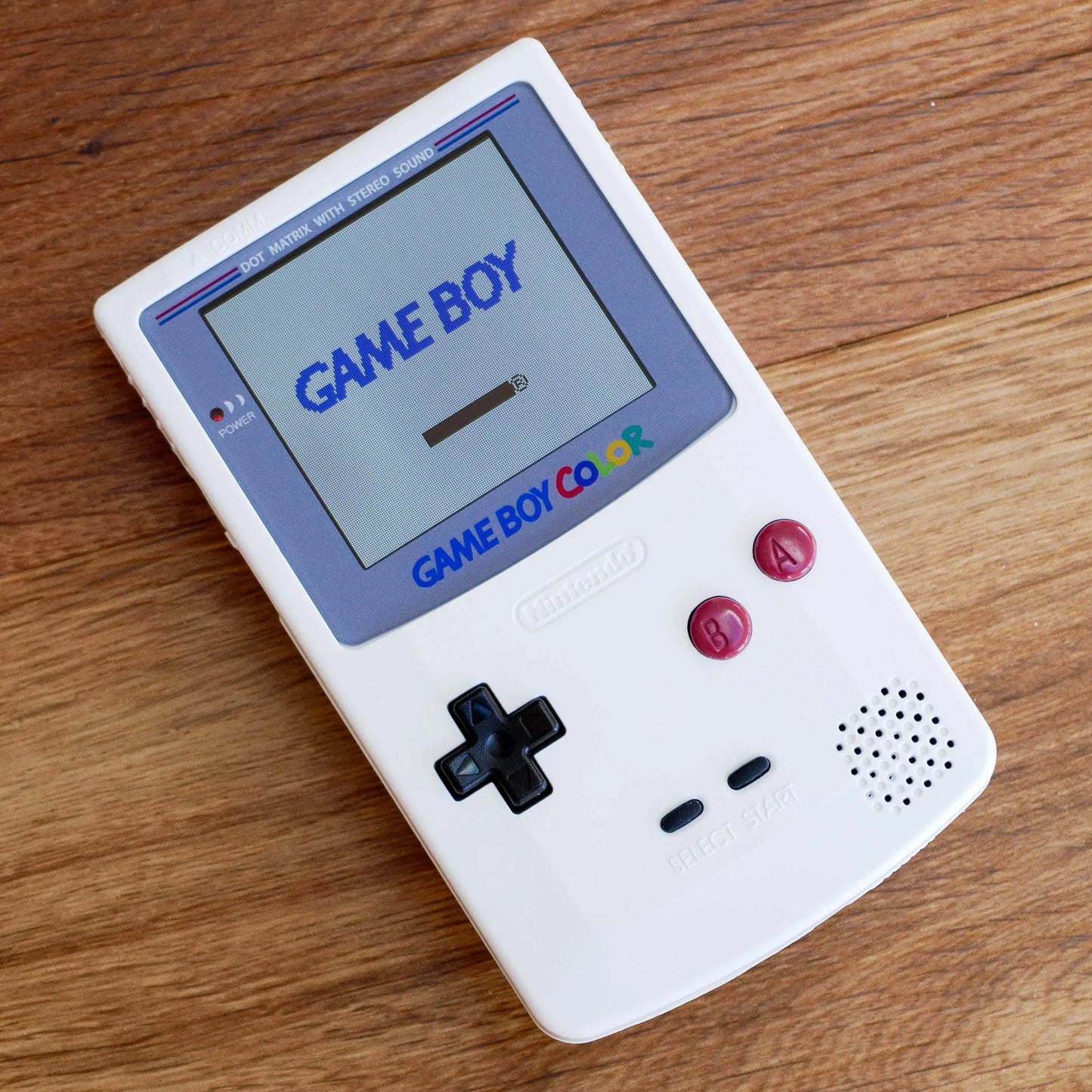 White Game Boy Color on a wooden surface robot retro