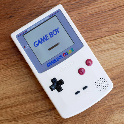 White Game Boy Color on a wooden surface robot retro