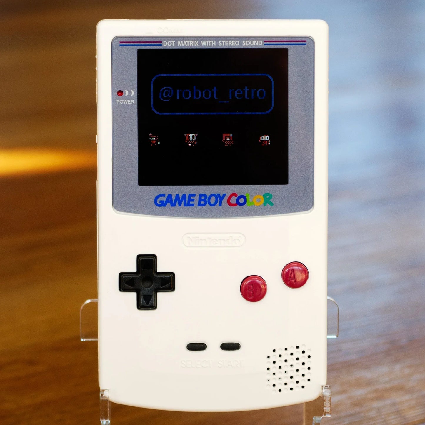 White Game Boy Color with 'Game Boy Color' branding on a wooden surface robot retro